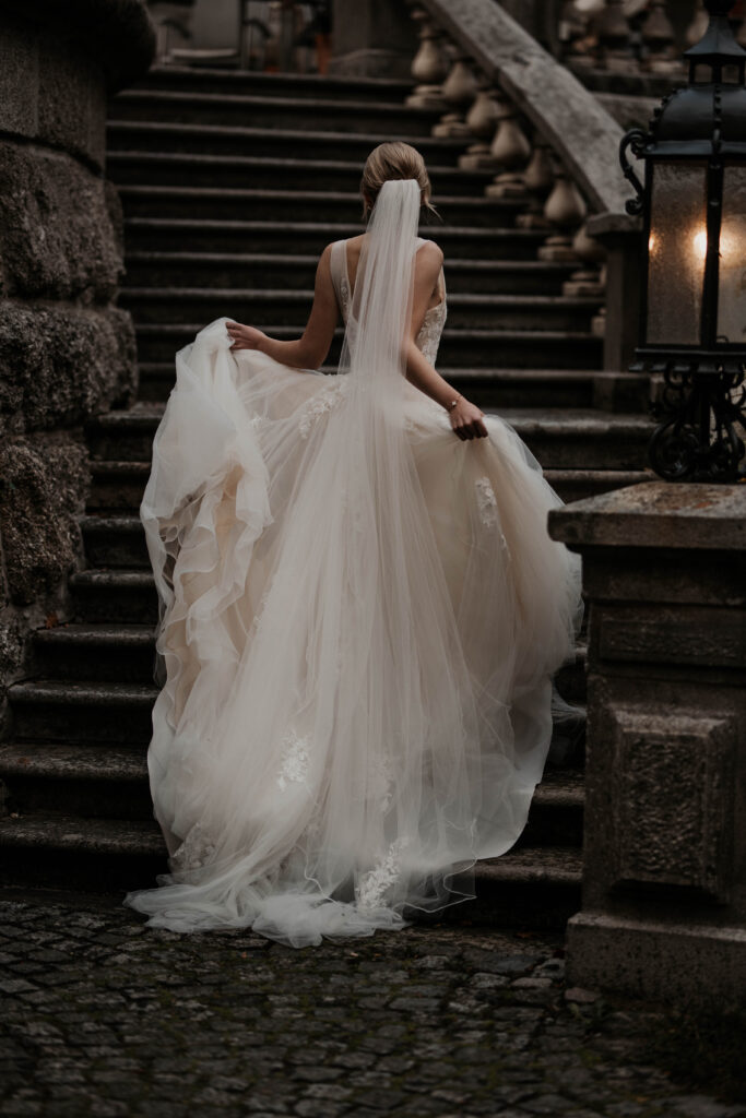Braut auf der Treppe mit langem Schleier und Brautkleid Schleppe